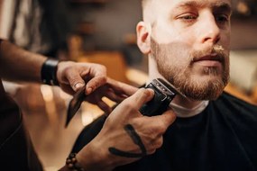 Φωτογραφία Male barber cutting beard of client in barber shop, South_agency