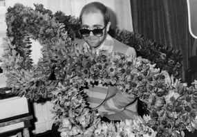 Φωτογραφία English Singer Elton John at his Arrival in Paris : Bunch of Flowers in The Shape of Glasses He Wears, December 1St, 1976